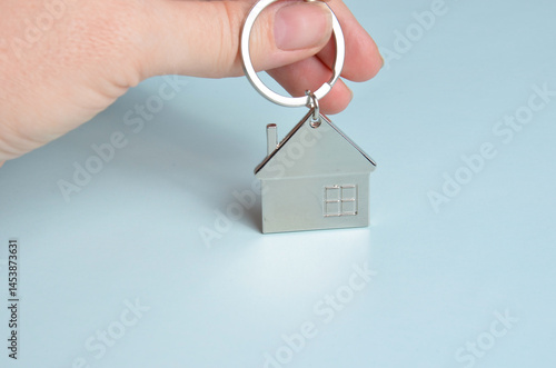 Metal keychain in the shape of a house. Blue background.