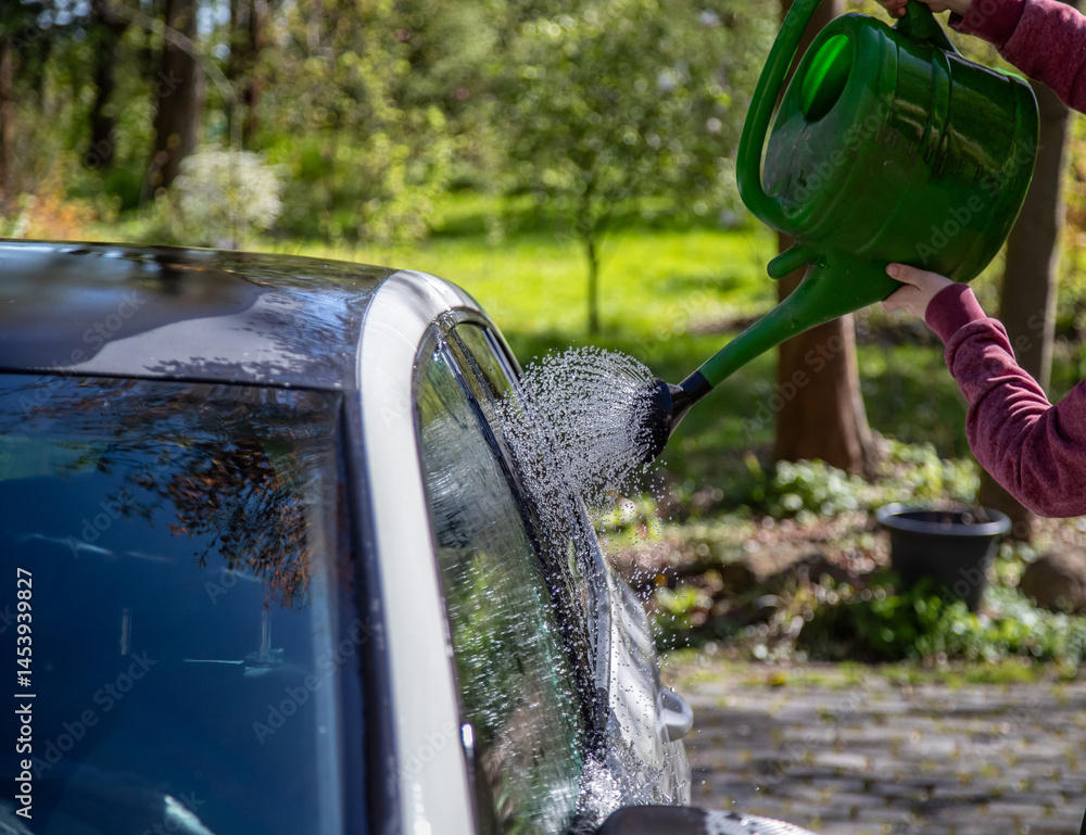 Auto abwaschen mit einer Gießkanne und viel Wasser