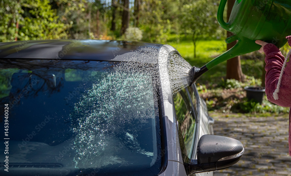 Auto abwaschen mit einer Gießkanne und viel Wasser