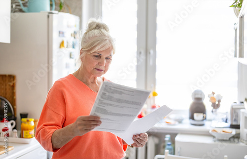 Senior woman looking through financial documents at home 

