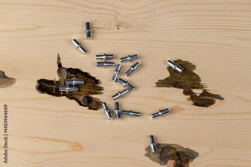 metal rivets for furniture are used to install shelves in cabinets, furniture metal fittings on a wooden board, closeup