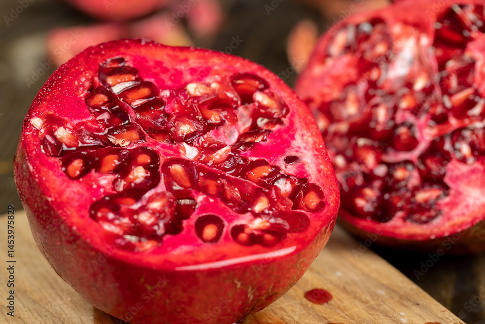 sliced ripe pomegranate on a black table, sweet red pomegranate cut into pieces during cooking, close up