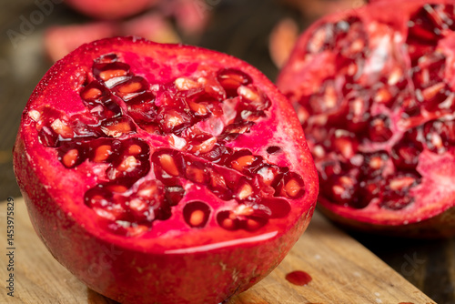 Obraz na płótnie sliced ripe pomegranate on a black table, sweet red pomegranate cut into pieces during cooking, close up w salonie