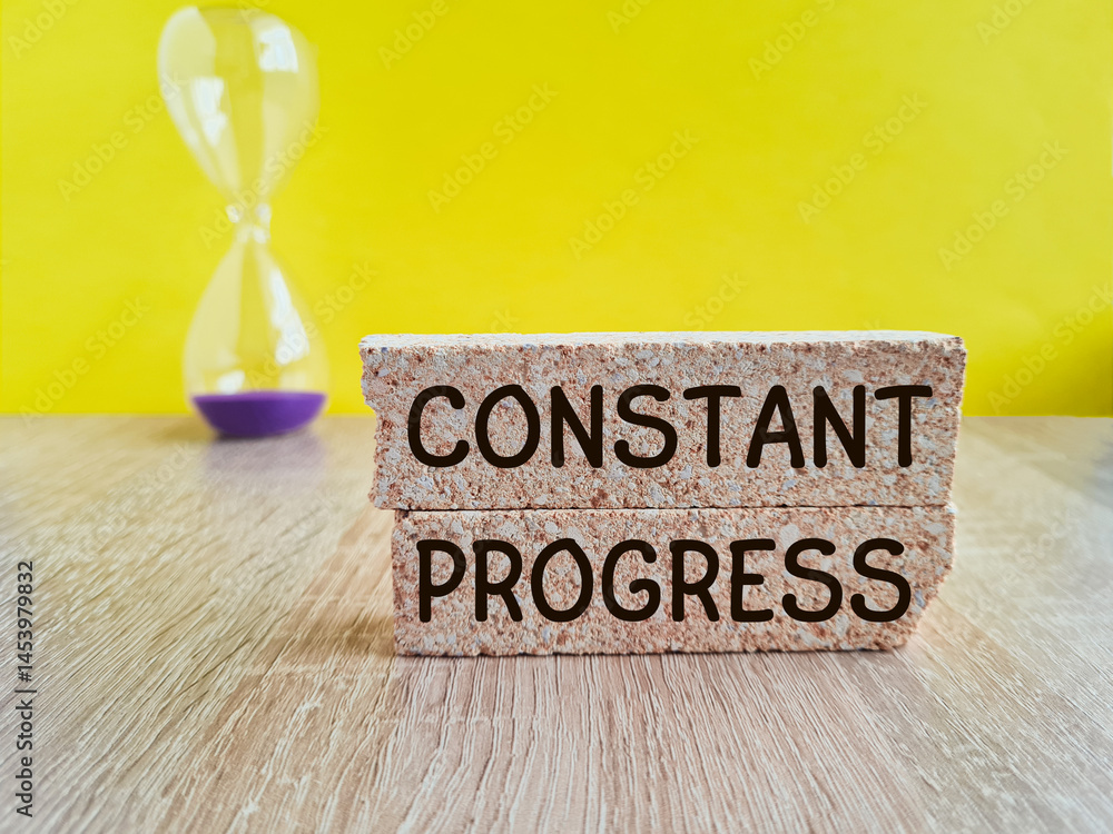 Constant Progress symbol. Brick blocks with concept words Constant Progress. Hourglass. Beautiful yellow background. Business concept.
