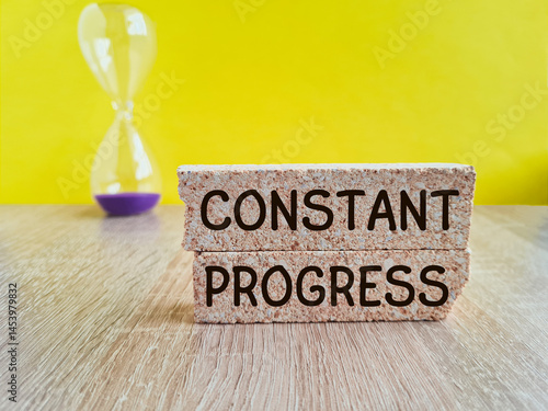 Obraz na płótnie Constant Progress symbol. Brick blocks with concept words Constant Progress. Hourglass. Beautiful yellow background. Business concept. w salonie