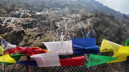 4k video footage of Waterfall flowing from the Himalayan mountains peaks at Annapurna Base Camp trek, Nepal with fluttering colorful prayer flags decoration