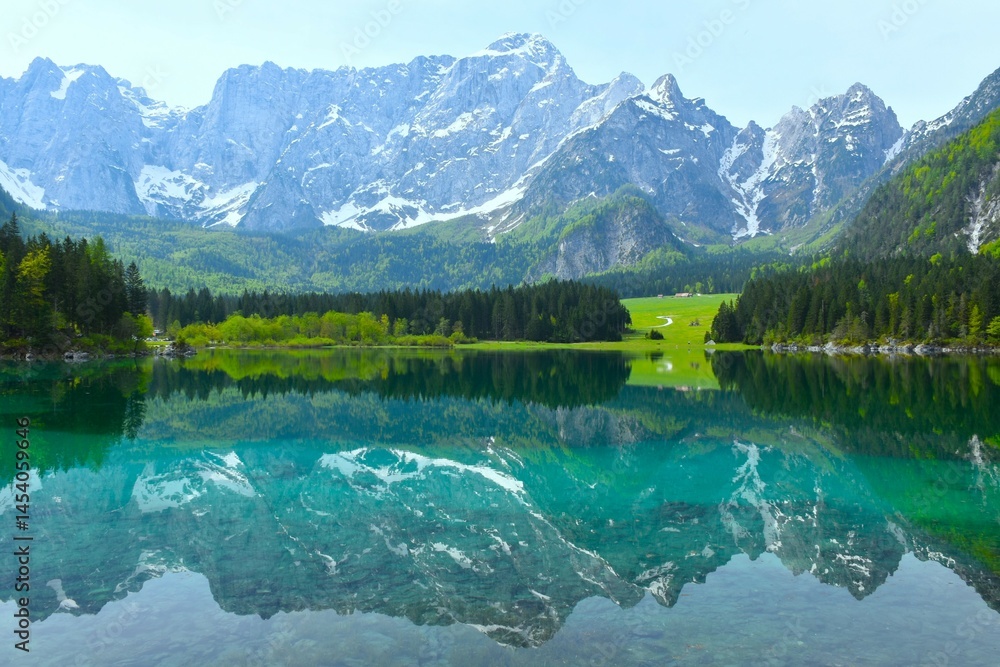 View of lago di Fusine superiore alpine lake and Mangart mountain peak in Julian alps above in municipality of Tarvisio, Italy