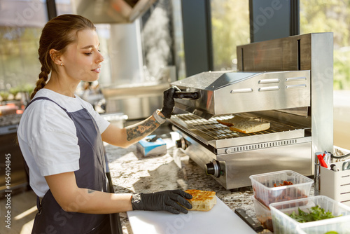 In a bright and modern kitchen, a young chef is skillfully crafting a truly delicious sandwich with care