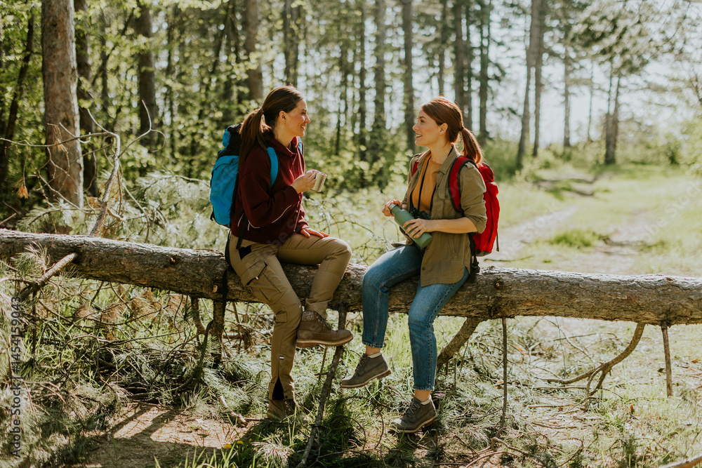Friends enjoy a refreshing break while hiking through a serene forest on a sunny afternoon