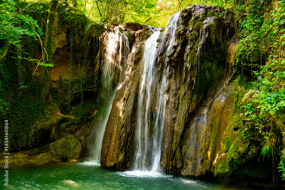 Hidden waterfall cascading through lush green forest in a serene natural oasis