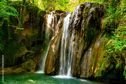 Obraz na płótnie Hidden waterfall cascading through lush green forest in a serene natural oasis w salonie