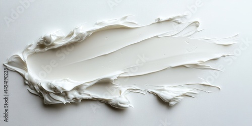 Obraz na płótnie A white blob of cream is spread across a white background. The cream is thick and has a slightly grainy texture. Concept of messiness and disarray, as the cream is not evenly spread w salonie