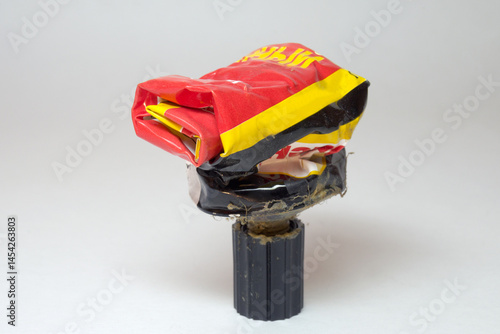 adhesive, metal squeeze tube, rolled, spent, stands on screw cap, bright colorful packing, rubber based adhesive material, dried remains on surface