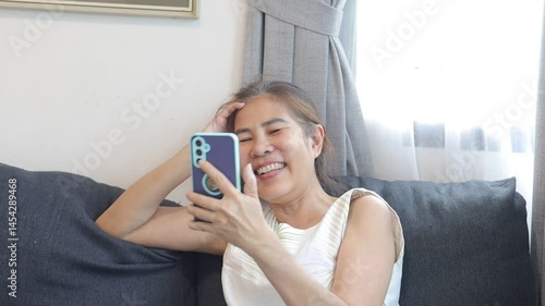 woman smiling while video chatting, holding phone