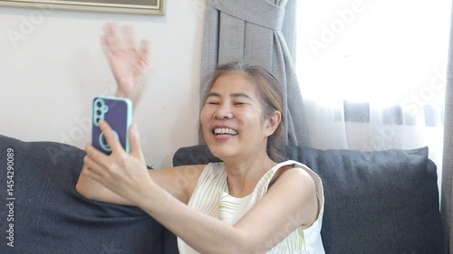 woman smiling while video chatting, holding phone