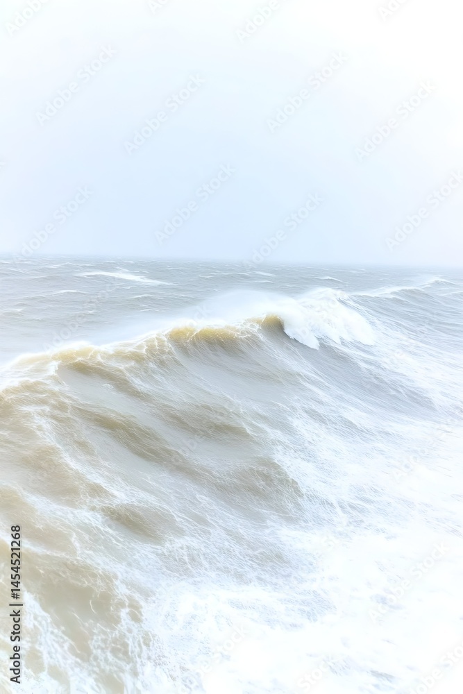 Fototapeta premium A powerful ocean wave crashes under a stormy, pale sky