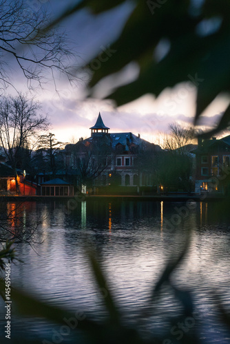 Charming Lakefront Mansion Framed by Leaves at Dusk – Reflections and Twilight Ambience