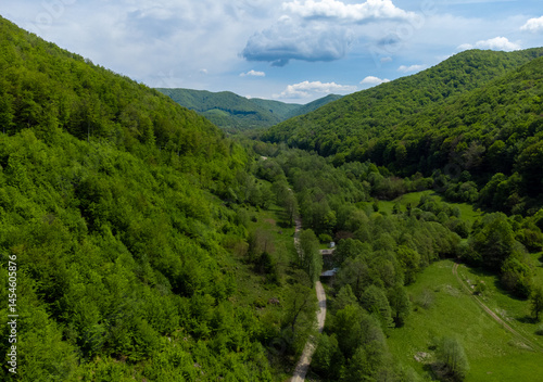 Obraz na płótnie Aerial view of a valley between hills with green deciduous forests w salonie
