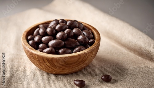 dark chocolate dragee in olive wood bowl on linen background