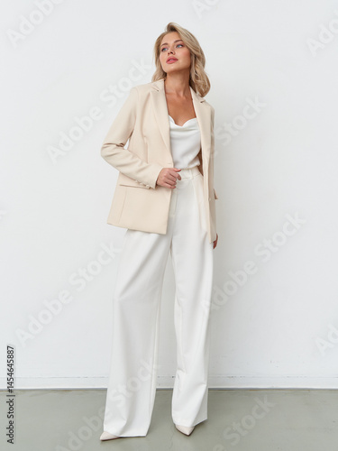 Elegant female model posing in stylish neutral suit within modern studio setting