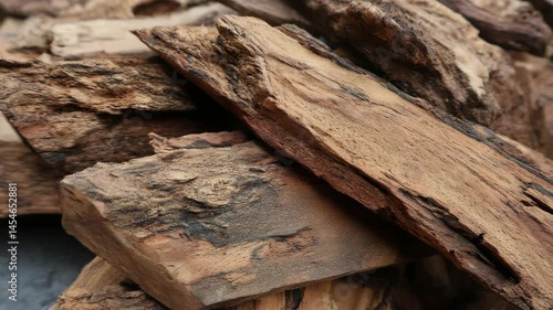Close-up of natural aromatic Agarwood, also known as Oudh or Aloeswood, stacked irregularly showing the textured surface and earthy tones