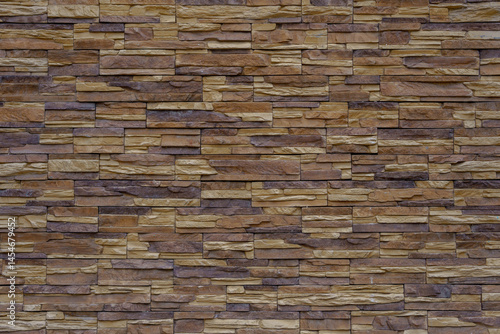 Wall made of brown and beige vintage bricks. The bricks are laid in a pattern.