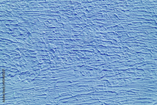 A wall with a blue paint that has a texture. The texture is made up of lines and swirls.