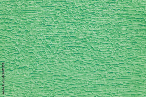 A wall with a green paint that has a texture. The texture is made up of lines and swirls.