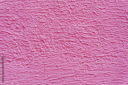 A wall with a pink paint that has a texture. The texture is made up of lines and swirls.