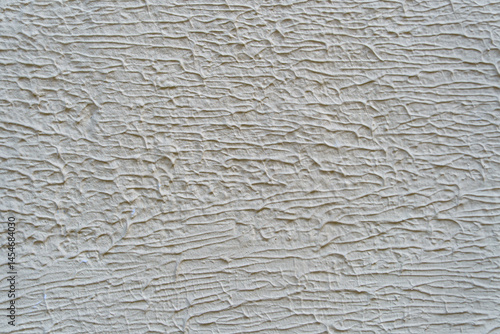 A wall with a white paint that has a texture. The texture is made up of lines and swirls.