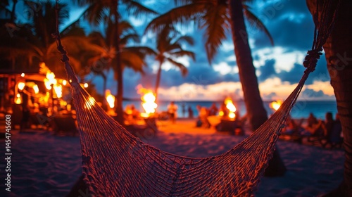 Obraz na płótnie Close up of hammock mesh stretched between palm trees, tiki torches and beach party in background w salonie