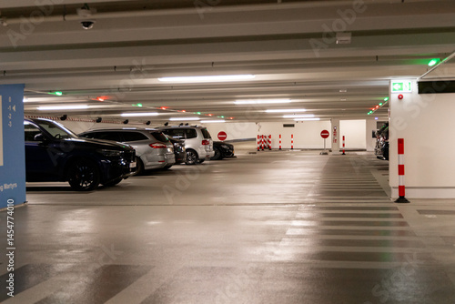  Parking garage interior showcasing parked cars, illuminated signs, and directional indicators for drivers