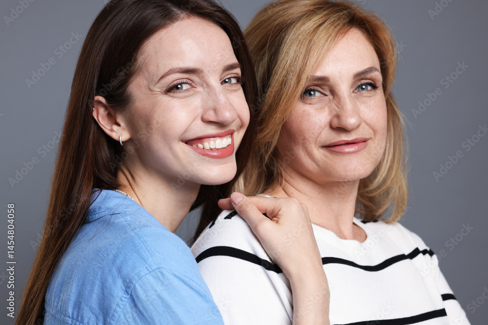 Portrait of mother and daughter on grey background Portrait of mother and daughter on grey background
