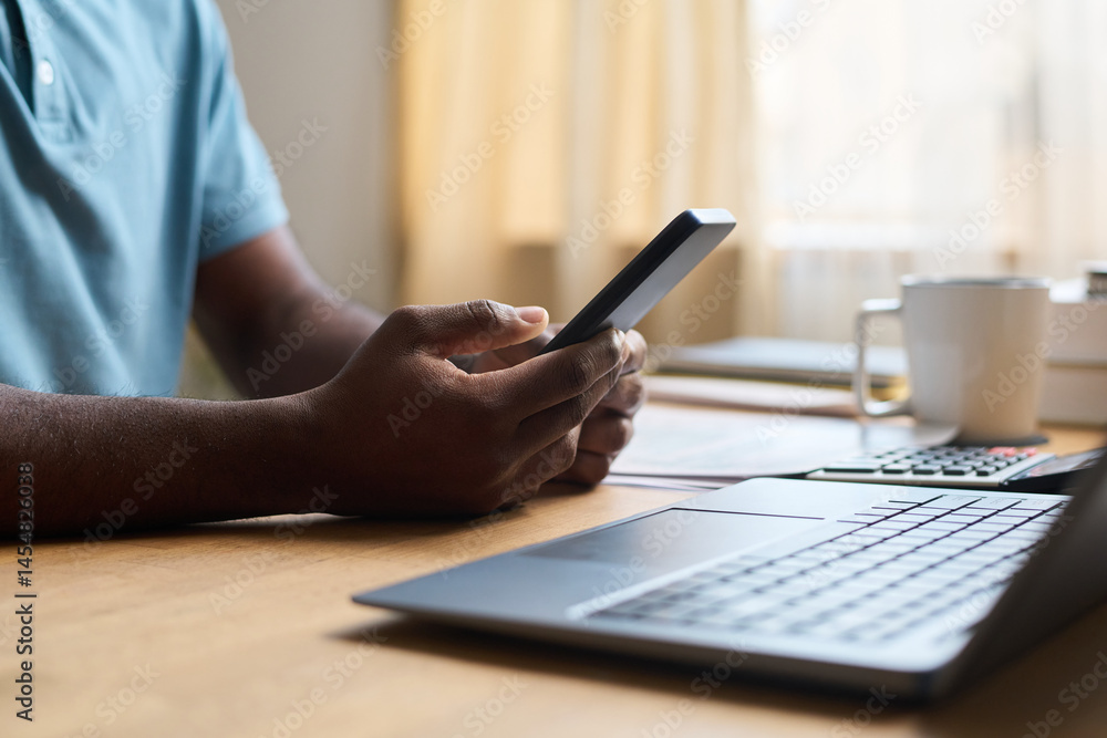 custom made wallpaper toronto digitalCloseup of unrecognizable African American man sitting at desk with laptop on it, checking email on smartphone