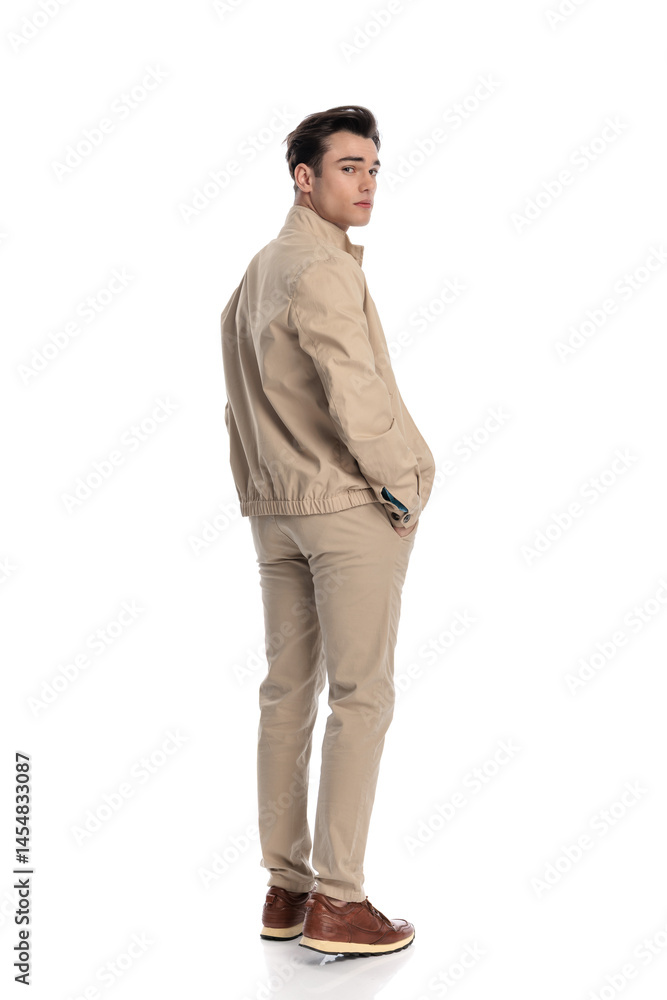 Fototapeta premium sexy young man looking behind while walking with hands in pockets