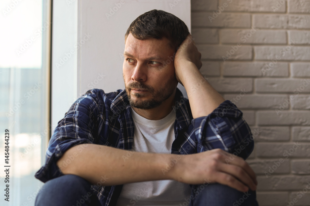 Obraz premium Depressed man sitting near window at home