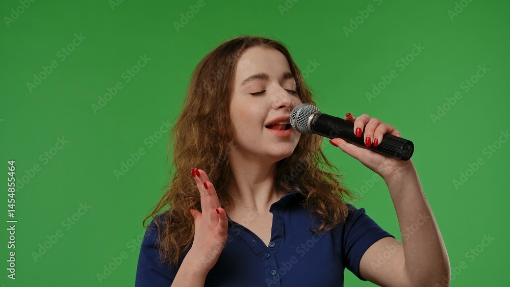 Φωτογραφία Teenage girl posing at camera smiling and singing song in karaoke microphone, positive expression, isolated on chroma key green screen studio background mockup