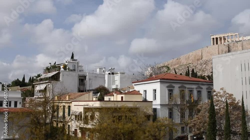Captivating Greece view overlooking rooftops around historical Acropolis in Athens. Experience the beauty of traditional buildings and the vibrant Greek landscape under a clear blue sky.