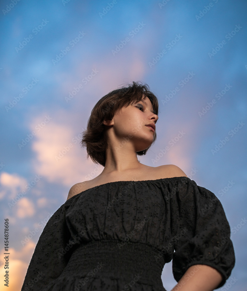 Portrait of beautiful serious teen girl against cloudy sky