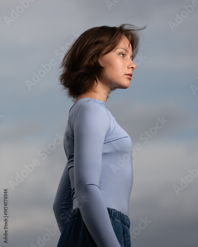 Obraz na płótnie Portrait of beautiful serious teen girl against cloudy sky on windy day w salonie