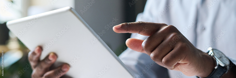 Closeup of hands of unrecognizable black male businessman sitting in office, using digital tablet, header