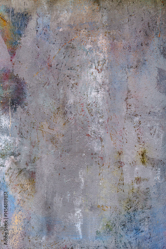 A wall with lots of paint splashes. The wall is grey and the paint is a mix of colours.