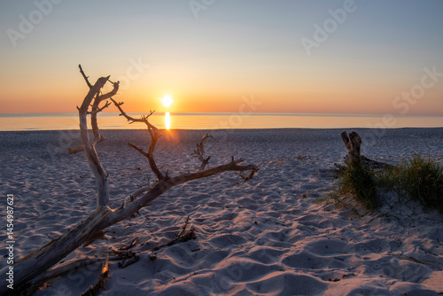 Fototapeta Naklejka Na Ścianę i Meble -  Sunset over the Baltic Sea illuminating the serene Darß Peninsula beach in Germany