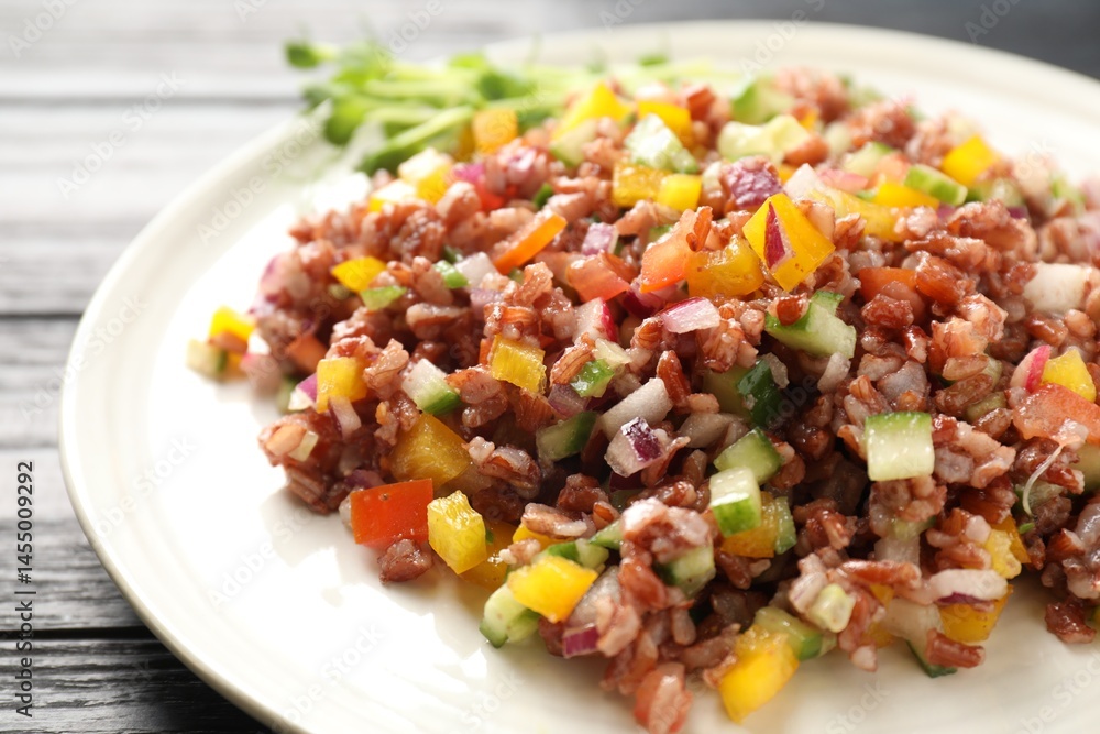 Tasty salad with brown rice on black wooden table, closeup Tasty salad with brown rice on black wooden table, closeup