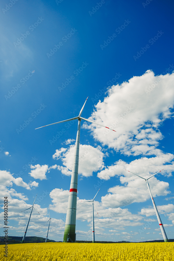 Wind turbines in a yellow field against a blue sky. Ecological energy production by windmills in rural areas in Europe.
