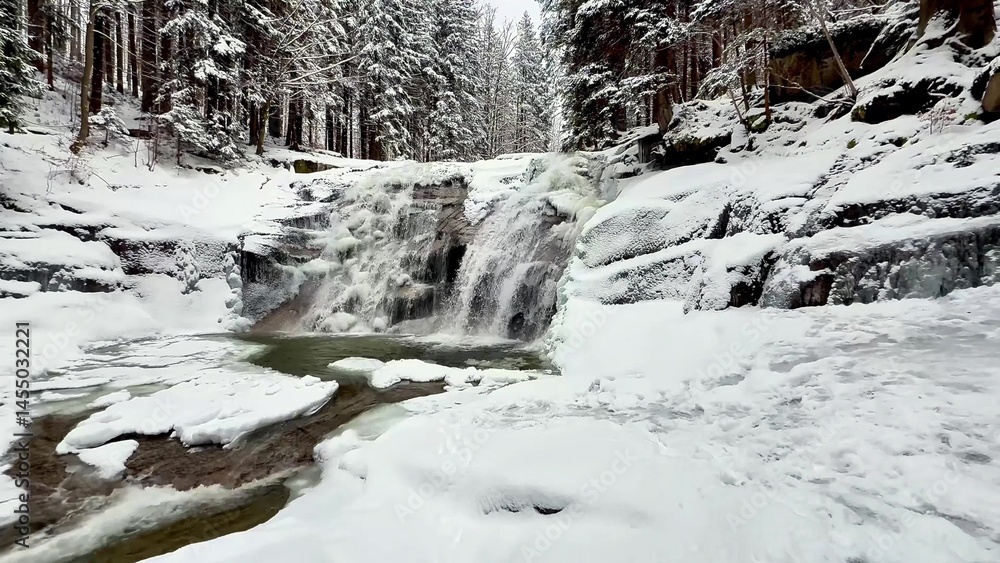 Obraz premium A frozen mountain river with a waterfall in a winter forest