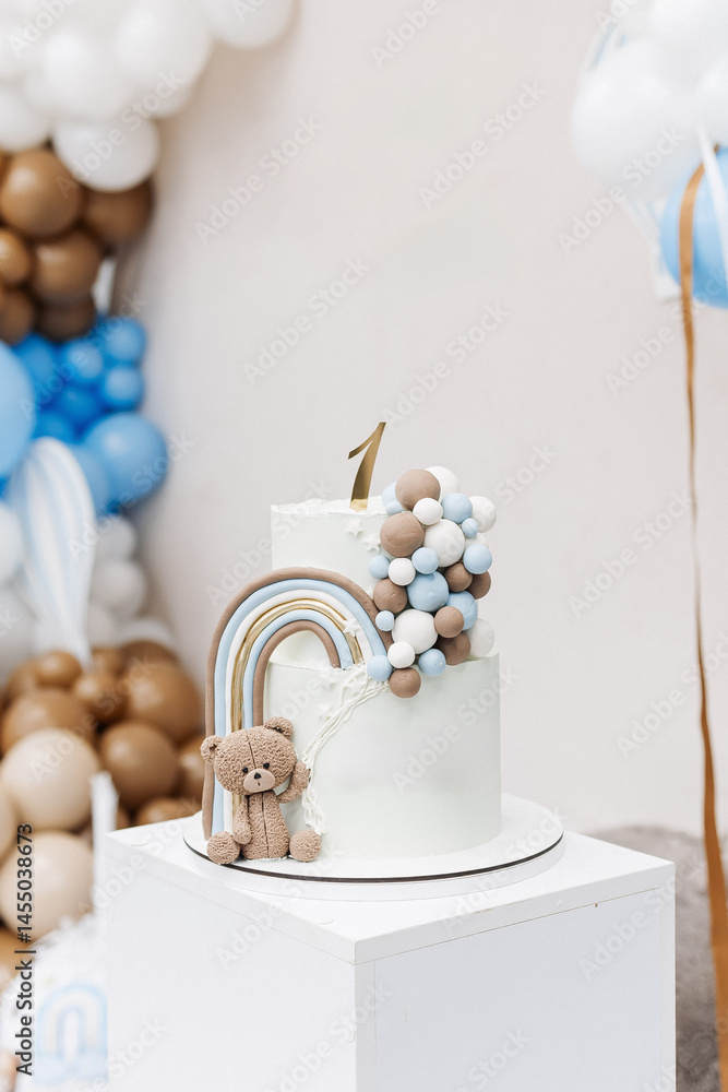 Two-story sweet cake decorated with a teddy bear for a birthday celebration. Cake for a child's first birthday. CAKE for a one-year-old child.