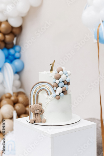 Two-story sweet cake decorated with a teddy bear for a birthday celebration. Cake for a child's first birthday. CAKE for a one-year-old child.