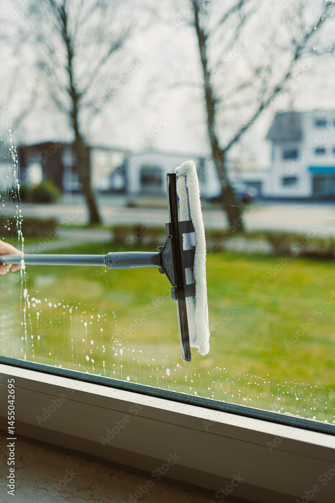 Professional cleaning worker washes windows with special equipment. Woman washes windows with mop and glass cleaner. House cleaning.