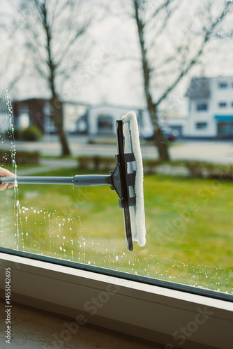 Obraz na płótnie Professional cleaning worker washes windows with special equipment. Woman washes windows with mop and glass cleaner. House cleaning. w salonie